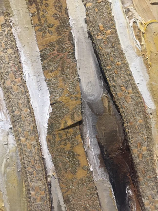 Detailed shot of a textured mixed-media artwork blending paint and fabric elements.
