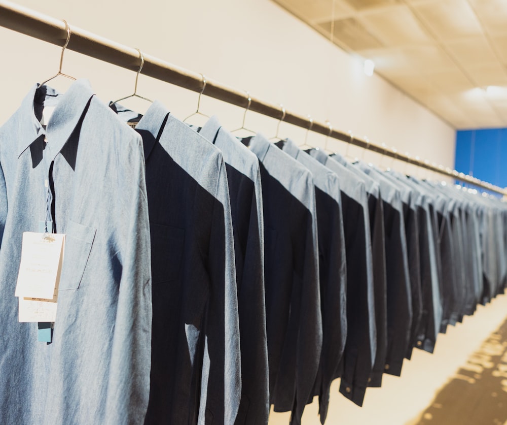 gray dress shirts hanging on brown pole