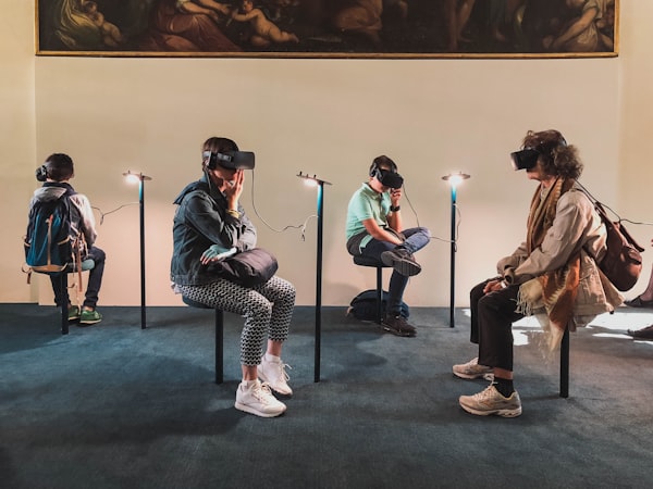 four people sitting on stools and wearing virtual reality headsets