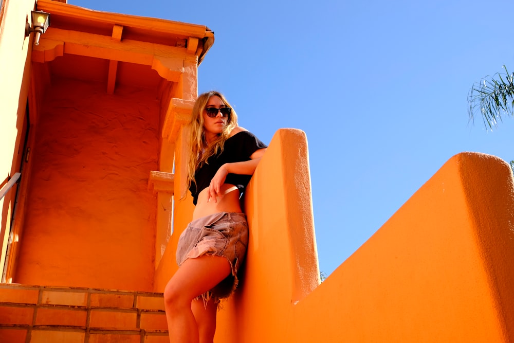 woman leaning beside orange wall