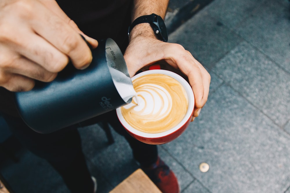 person pouring cream on coffee