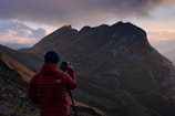 A dynamic shot of a photographer capturing a mountain sunrise, gear branded with Red Water Lake.