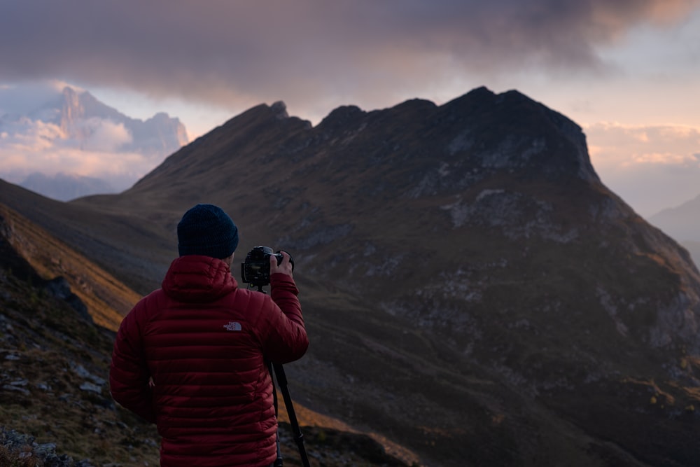 man aiming camera on mountain range