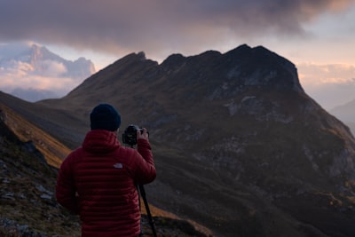 man aiming camera on mountain range baste zoom background