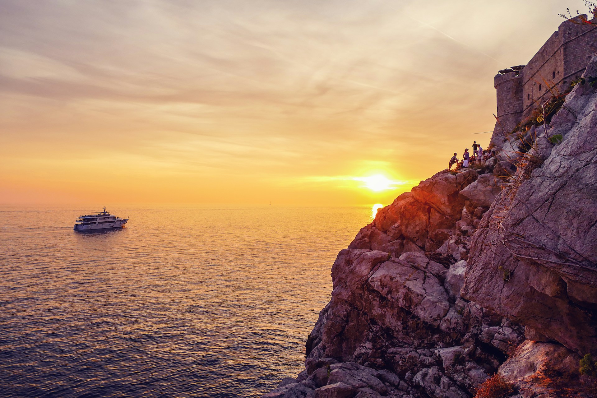 A vibrant sunset over the sparkling Adriatic Sea with a Sunmarine boat cruising near the Dalmatian coast.