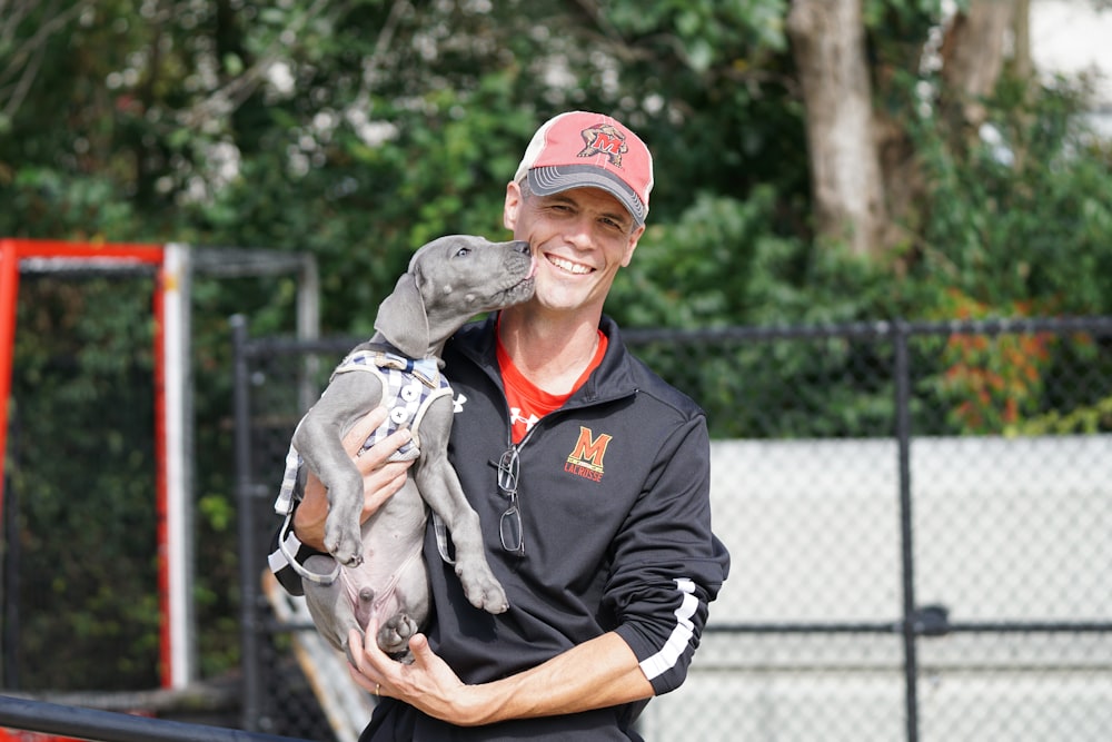 黒いアメリカンピットブルテリアの子犬を抱きながら微笑む男