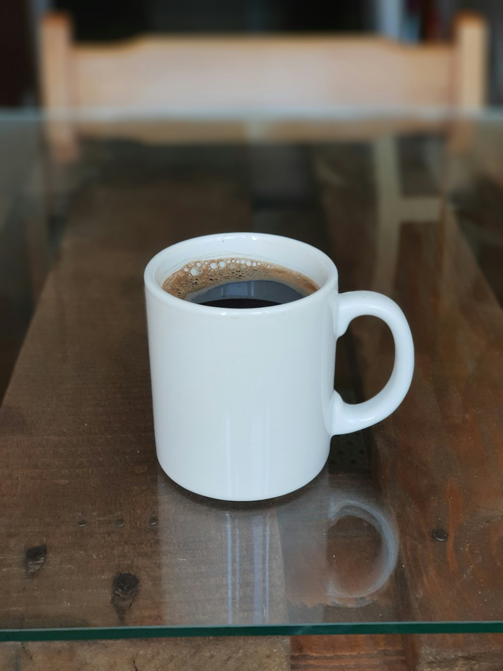 mug of coffee on glass-surface table close-up photography