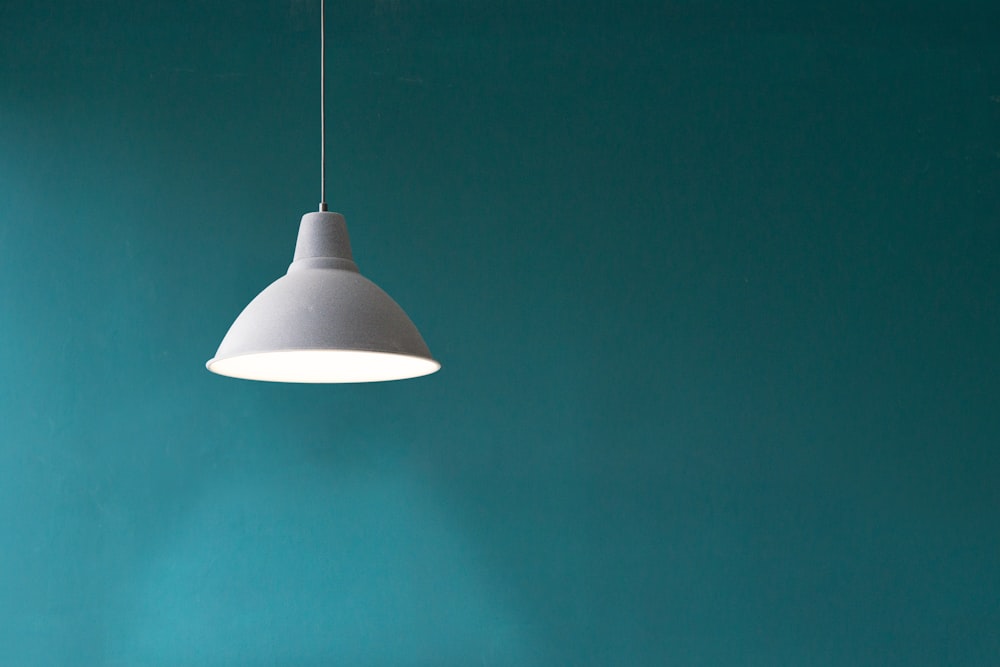 white pendant light in front of green wall