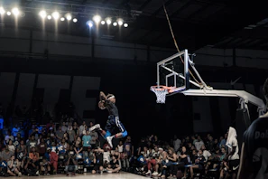 A basketball player soaring for a slam dunk in a packed arena