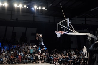 A heroic image of a basketball player making a slam dunk in a gymnasium.