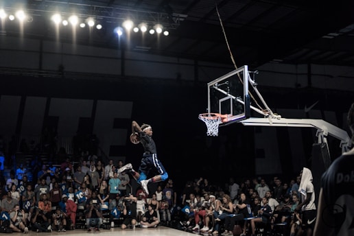 Energetic image of a basketball player jumping for a slam dunk in an indoor arena
