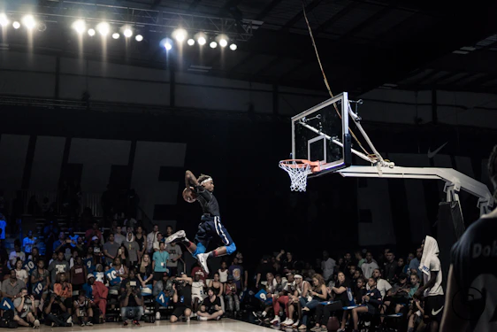 A dynamic basketball player soaring for a slam dunk under glowing arena lights with a vibrant Caribbean crowd in the background.