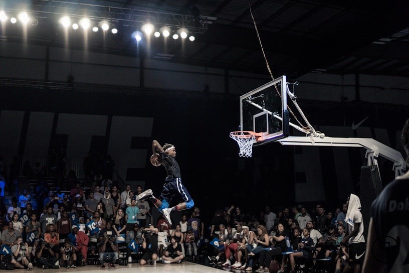 A vibrant action shot of a Cosmos Basketball Club player making a slam dunk during a lively game.