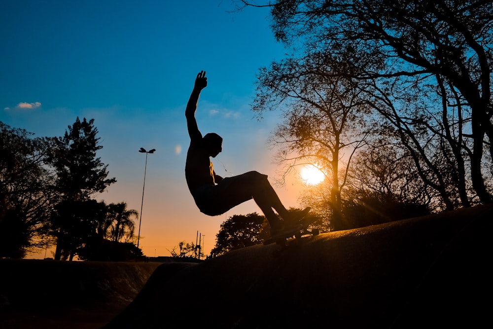 Silhouette eines Mannes, der bei Sonnenuntergang auf einem Skateboard fährt