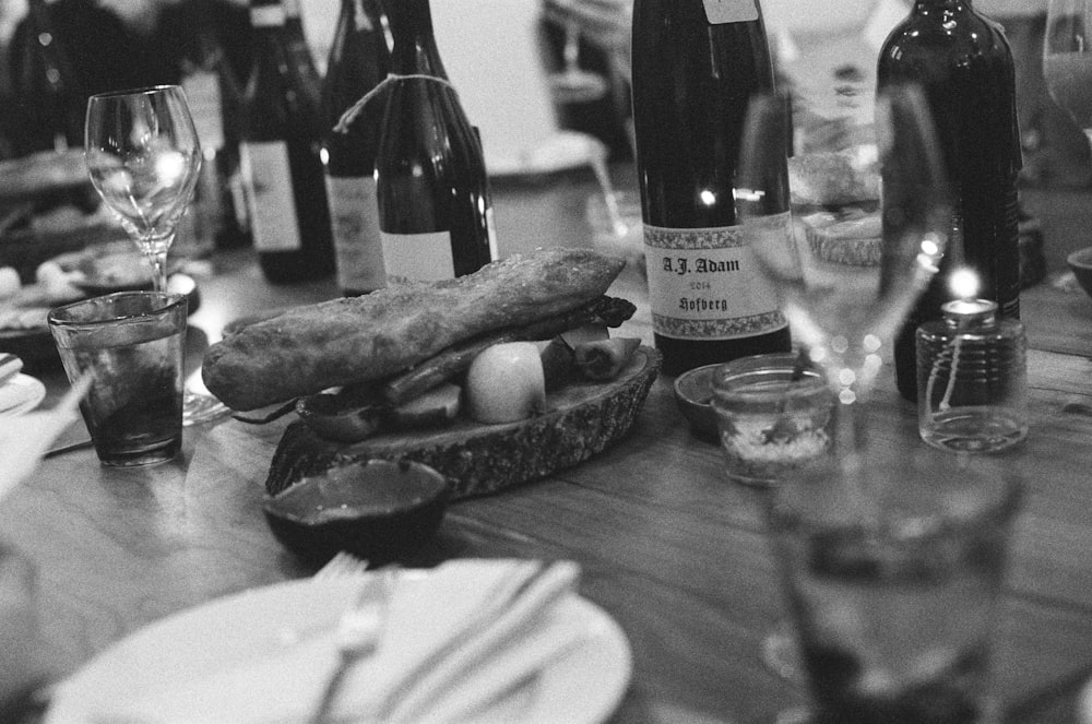 grayscale photo of glass and bottles on table