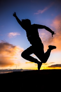 A silhouette of a figure mid-air performing a trick at sunset, capturing dynamic motion.