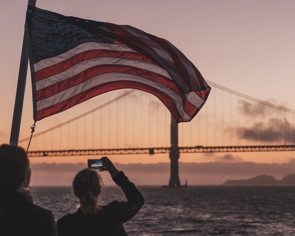 woman holding smartphone beside US flag