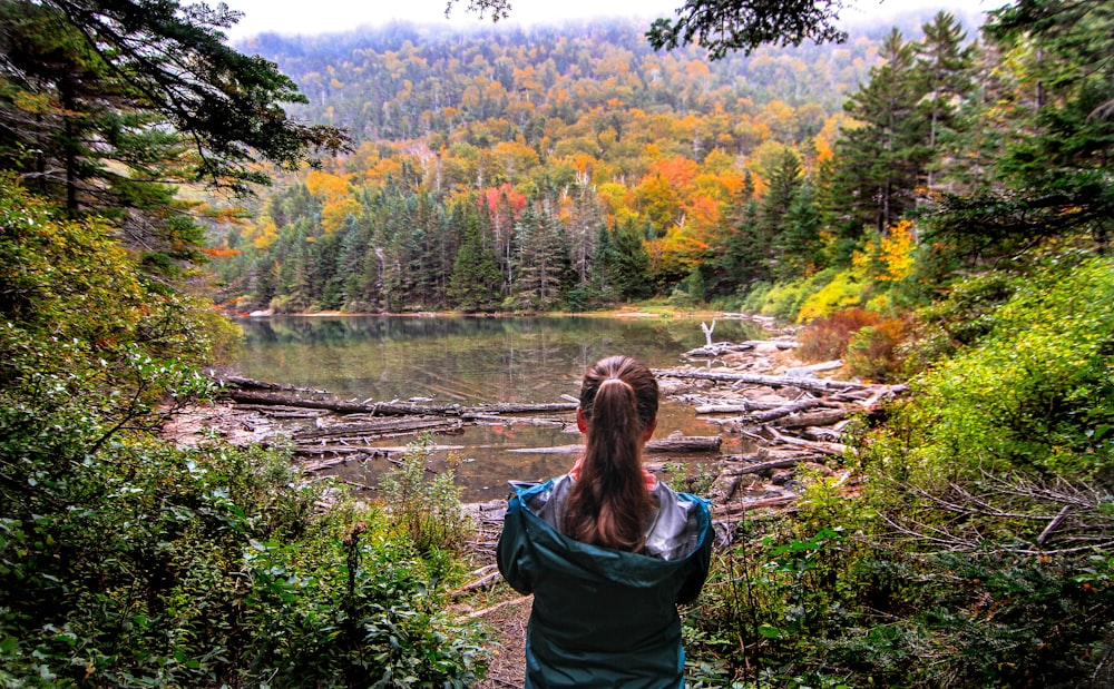 woman standing under tree in front of body of water during daytime