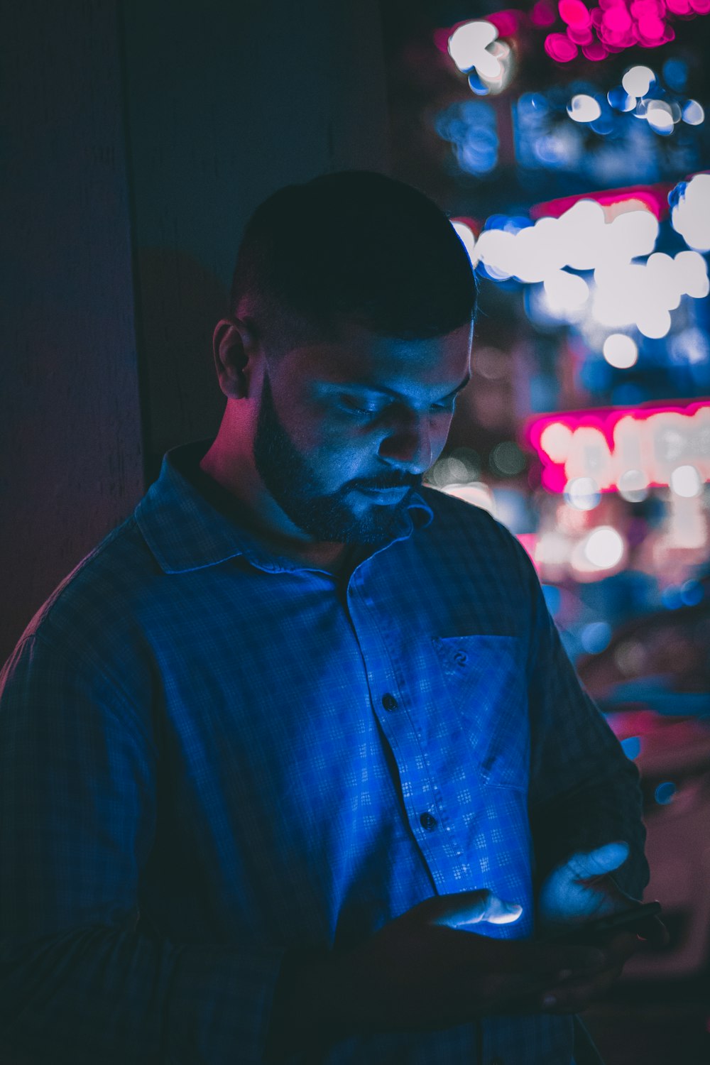 selective focus photography of man holding smartphone with bokeh photography background