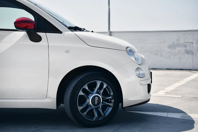A white compact car with a bright background, highlighting its well-maintained condition.