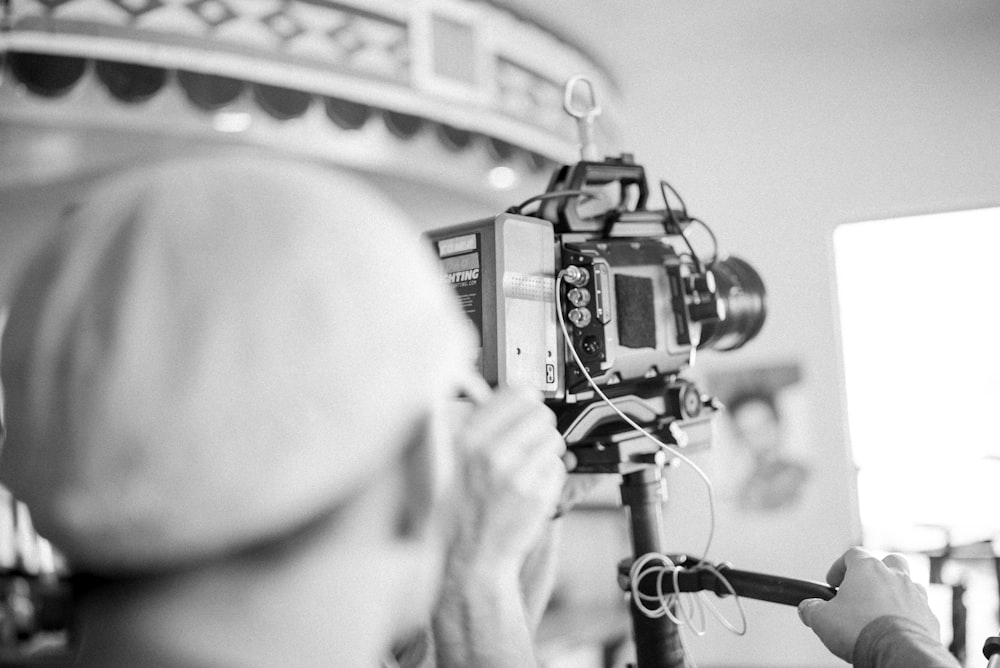 grayscale photo of man using a video camera