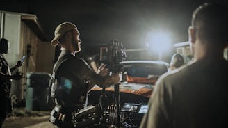 A behind-the-scenes shot of a film crew capturing a lively outdoor event at golden hour.