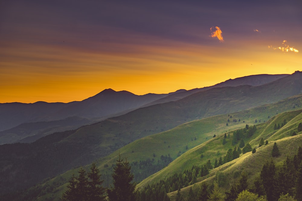 Veduta aerea delle colline verdi sotto il cielo blu e arancione