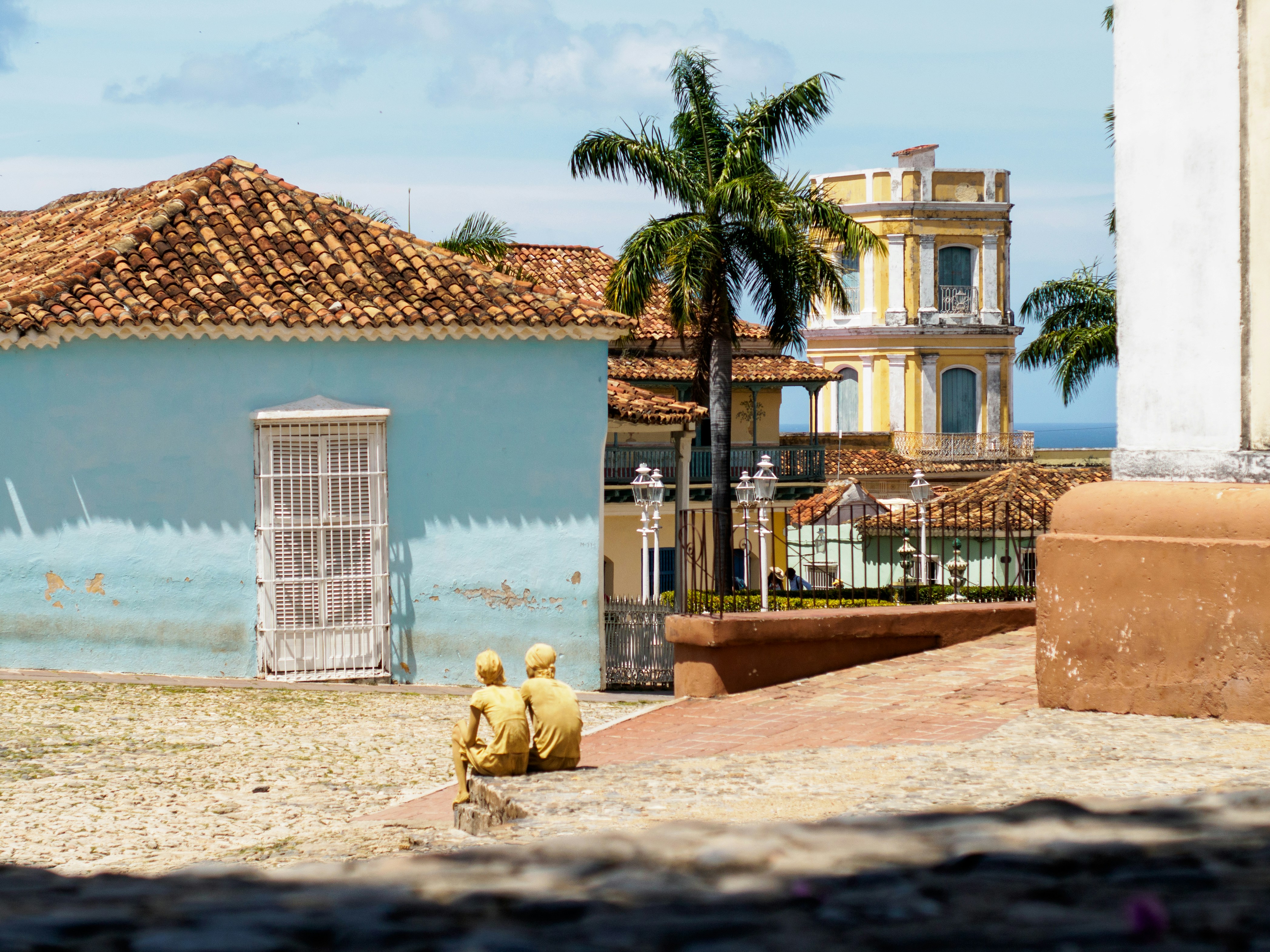 In the front there are two “figures”, two younger Cubans, who are human sculptures to earn some money. In the moment of the picture they are taking a break from their work lovely set in the main plaza in Trinidad.