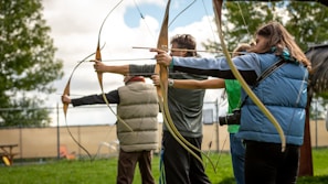 Group of participants practicing shooting stances under instructor's guidance outdoors.