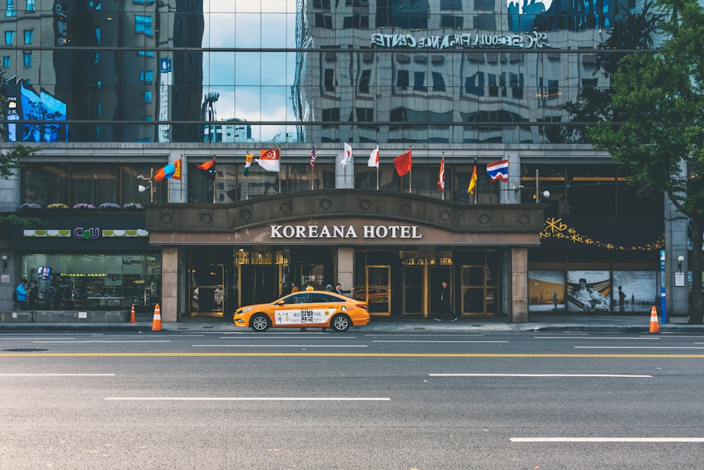 yellow car parked in front of Koreana Hotel during daytime