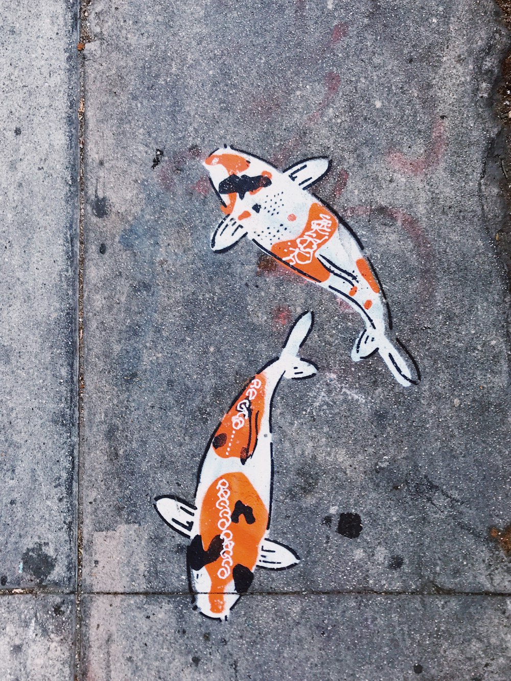 two orange-and-white koi fish paint on pavemnt