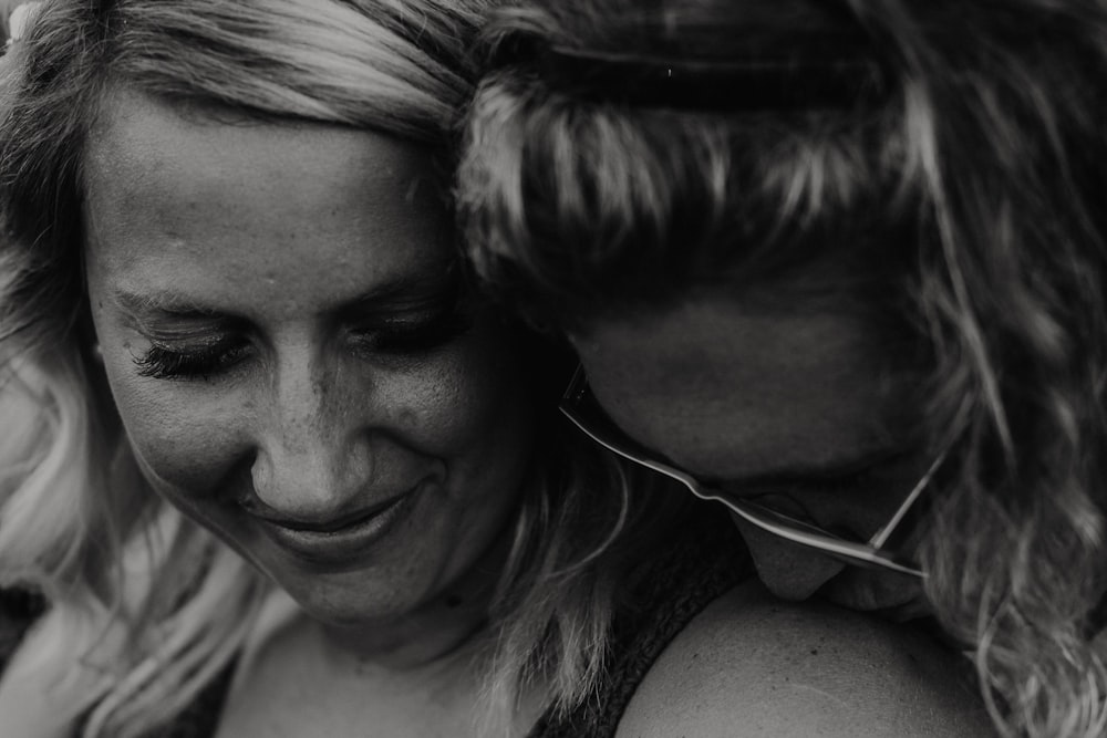 grayscale photography of man kissing woman's shoulder