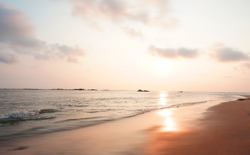 A tranquil beach at sunset with gentle waves and soft sand.