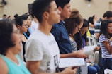man wearing white crew-neck T-shirt holding book