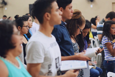 man wearing white crew-neck T-shirt holding book
