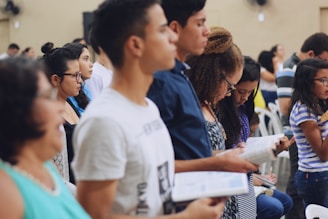 man wearing white crew-neck T-shirt holding book