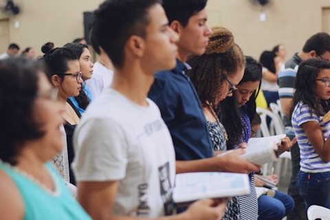 man wearing white crew-neck T-shirt holding book