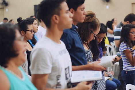 man wearing white crew-neck T-shirt holding book