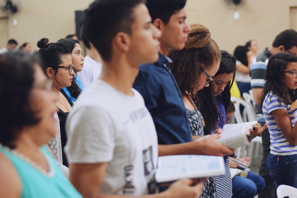 hombre con camiseta blanca de cuello redondo sosteniendo un libro