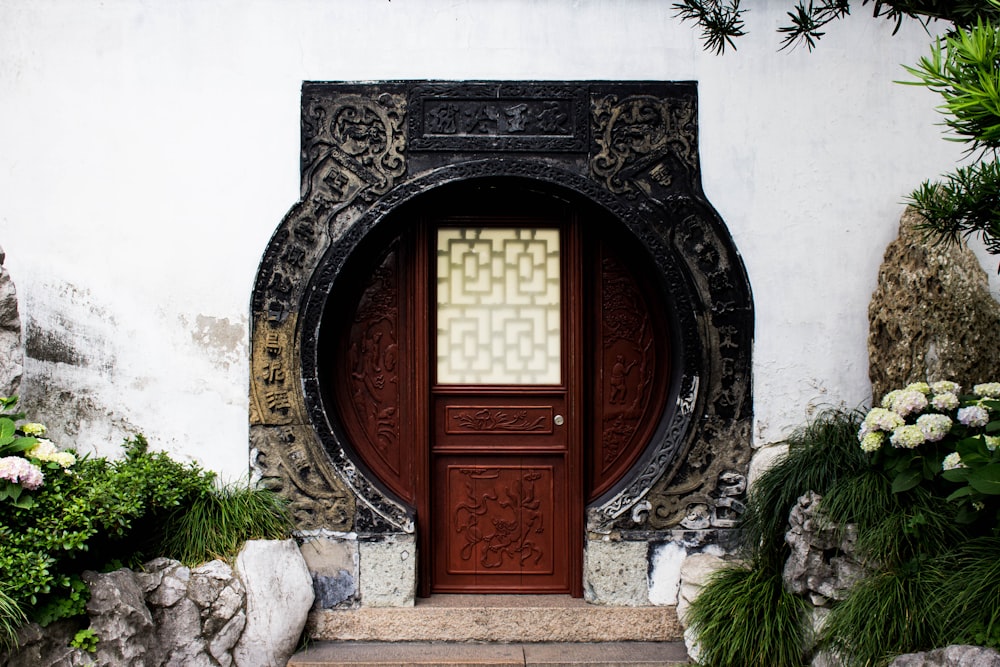 close-up photography of closed wooden door near tree and plants