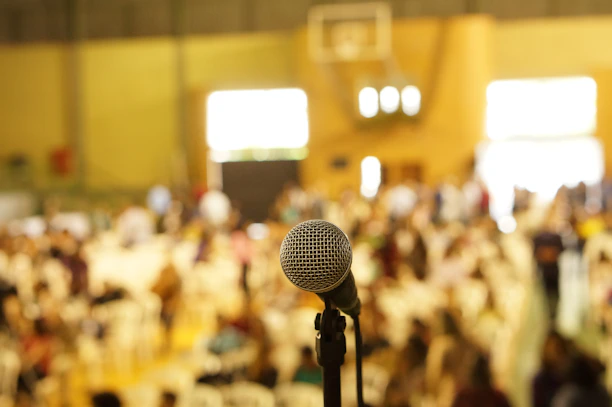 Close-up of a microphone with a blurred audience in the background.