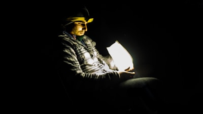A person comfortably wearing the iRestore helmet while reading a book at home.