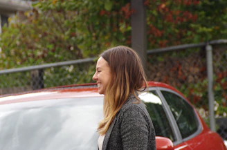 Smiling woman handing over car keys outside her home after a quick sale.