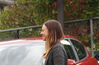 Smiling customer standing beside their freshly detailed car in Ontario.