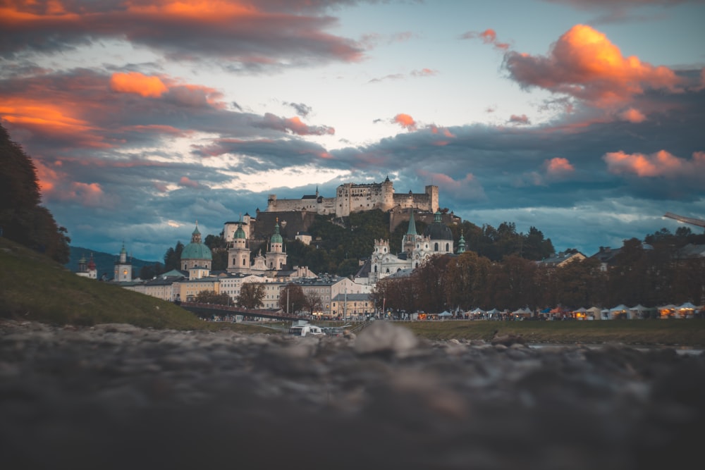 village below castle under cloudy sky during golden hour