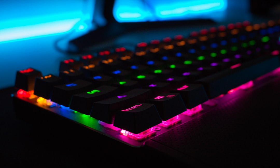 A rainbow gaming keyboard lays on a PC desk