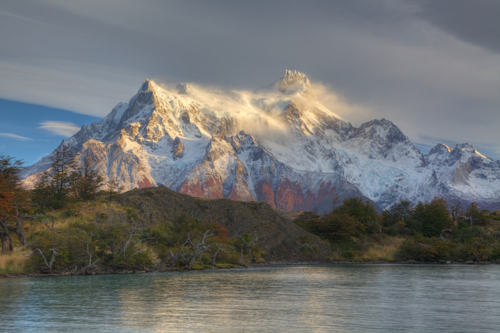 white mountain near lake painting