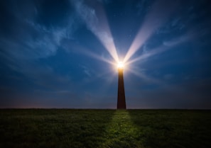 silhouette of light tower under cloudy sky