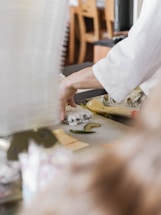A welcoming sushi chef preparing fresh rolls in a bright, modern kitchen.