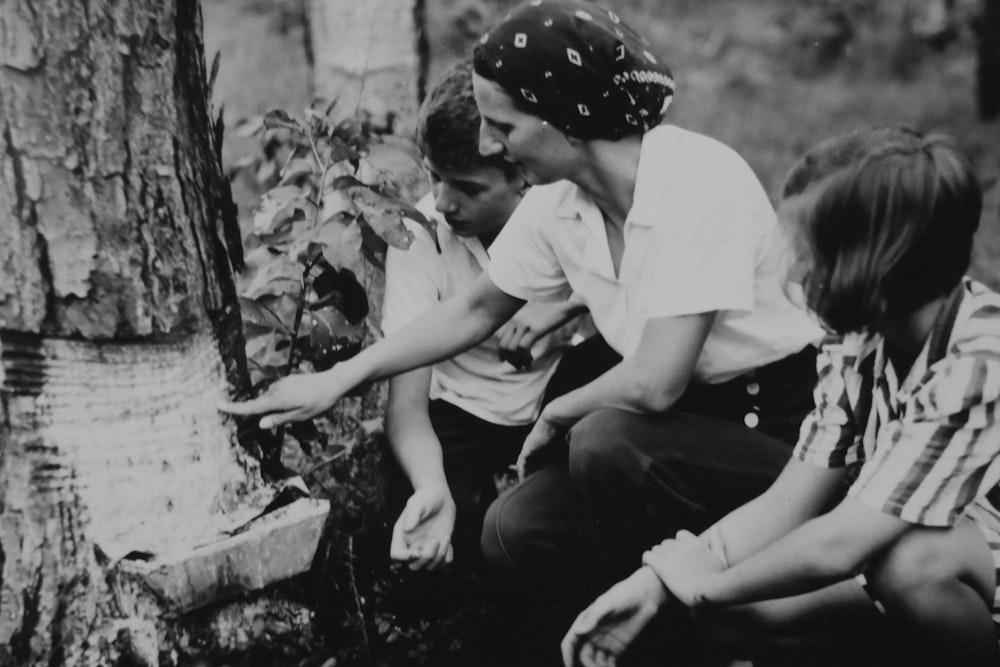 woman and two boys sitting in front of a tree